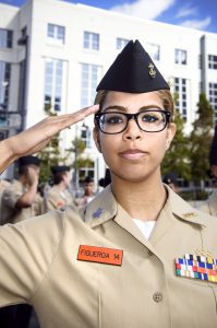 A woman in uniform saluting with one hand and two fingers raised.